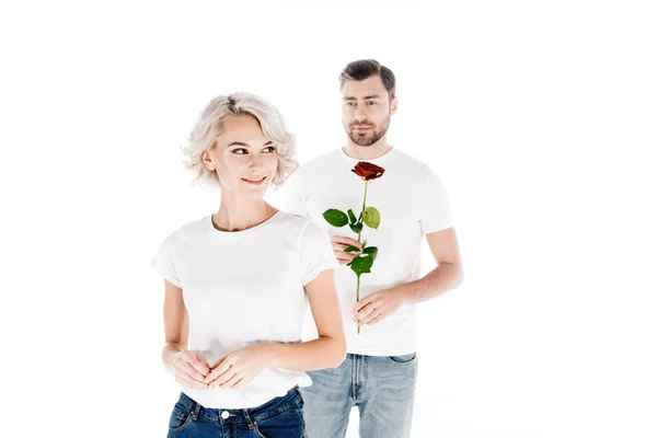 Schöne lächelnde Frau, die wegschaut, während Mann Blume isoliert auf weiß hält — Stockfoto