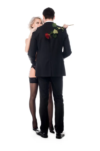 Приваблива пара обіймається, а жінка тримає квітку червону троянду ізольовано на білому — стокове фото