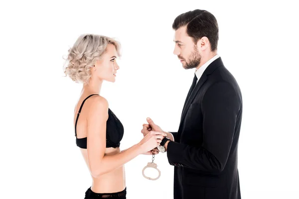 Пара молодих людей тримає наручники і дивиться один на одного ізольовано на білому — стокове фото
