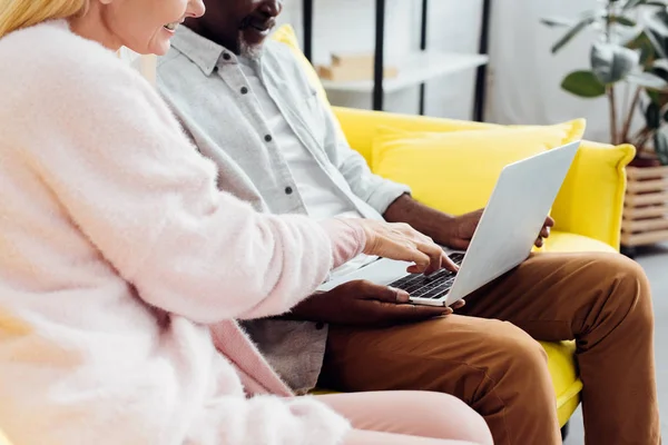 Close up of mature couple sitting on sofa and using laptop in living room — Stock Photo