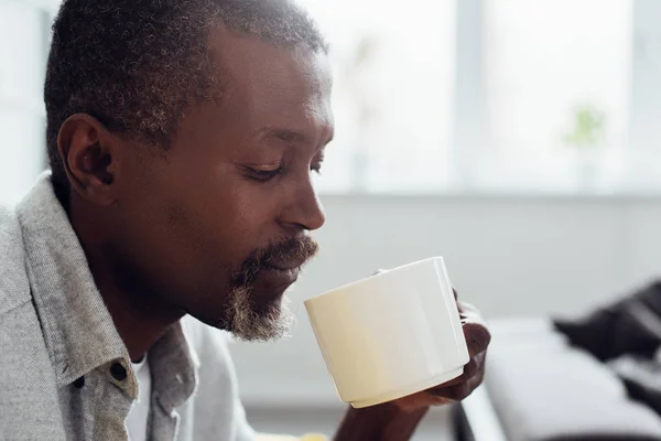 Gros plan d'un homme mûr afro-américain buvant du café dans le salon — Photo de stock