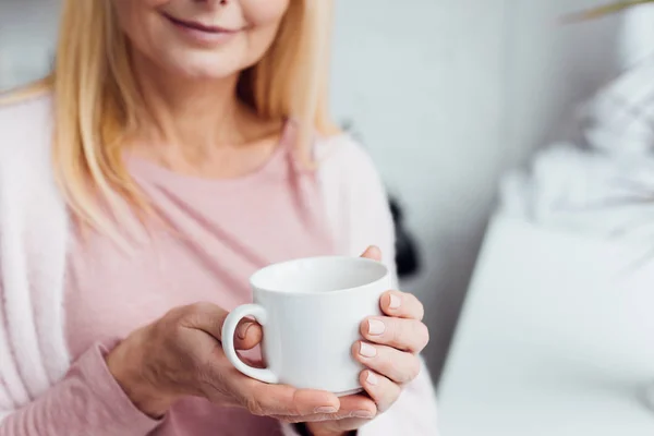 Close up de mulher loira madura segurando copo de café branco — Fotografia de Stock