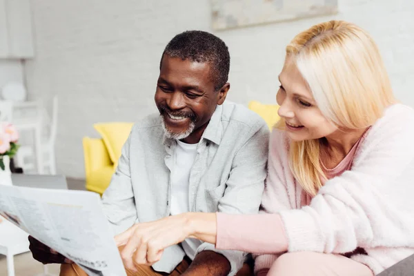 Happy african american man with mature woman reading newspaper together — Stock Photo