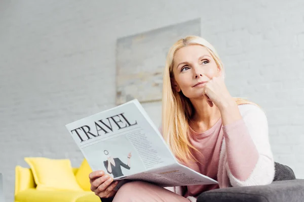Dreaming mature blonde woman holding newspaper — Stock Photo