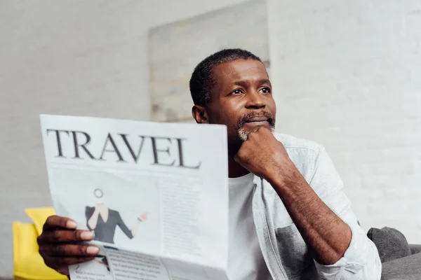 Hombre afroamericano soñando leyendo periódico de viajes - foto de stock