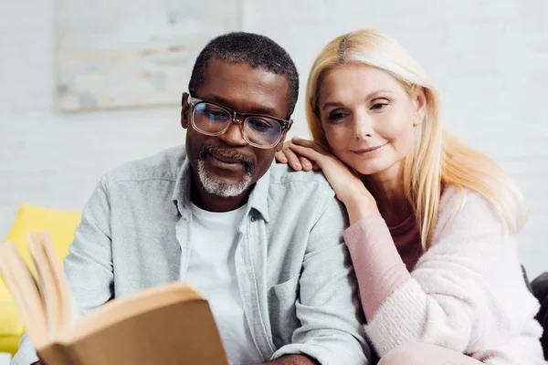Афроамериканський чоловік в окулярах і блондинка зріла жінка читає книгу разом — Stock Photo