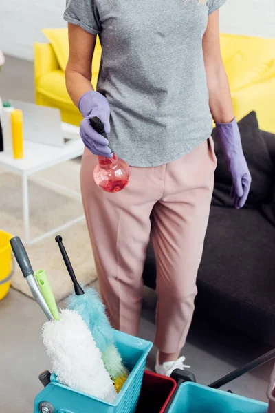 Close up of woman in rubber gloves with household supplies — Stock Photo