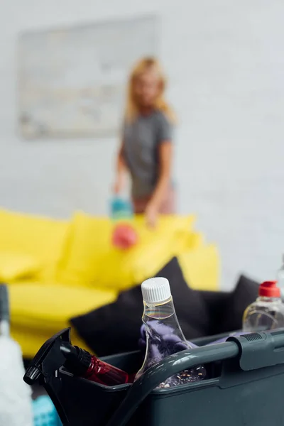 Housecleaning supplies in box with woman at background — Stock Photo