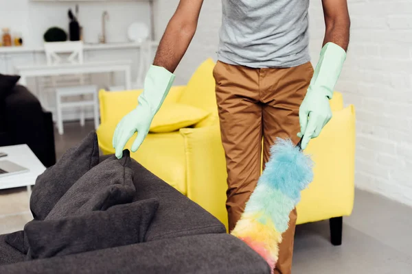 Cropped view of male african american hands in rubber gloves with duster — Stock Photo