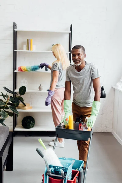 Mature couple doing housecleaning in living room together — Stock Photo