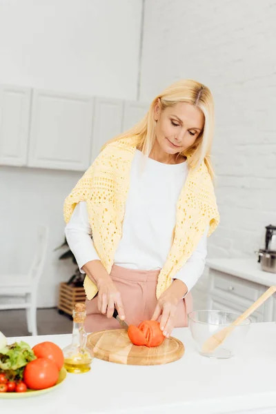 Attraktive blonde Frau schneidet Tomaten auf Schneidebrett — Stockfoto