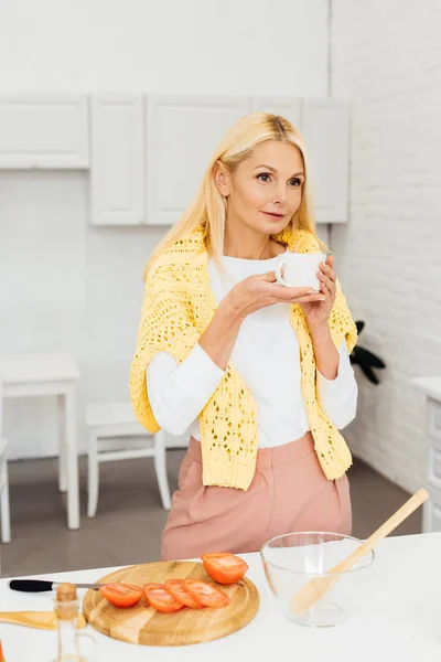 Schöne Frau steht mit einer Tasse Kaffee in der Küche — Stockfoto