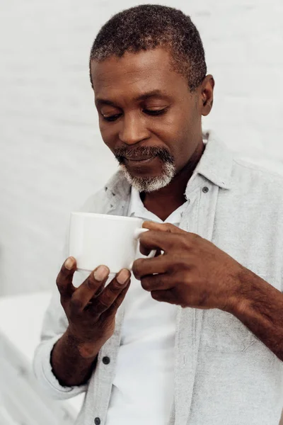 Афро-американський зрілий чоловік тримає білу чашку — стокове фото