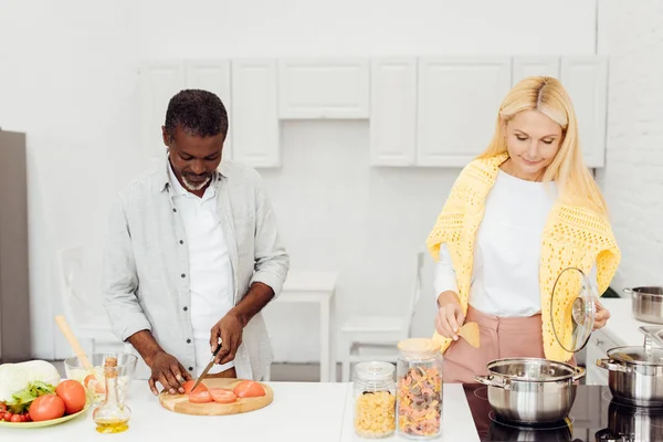 Hombre afroamericano y mujer madura preparando la cena juntos - foto de stock