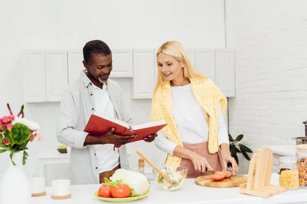 Feliz pareja cocinar la cena juntos en la cocina - foto de stock