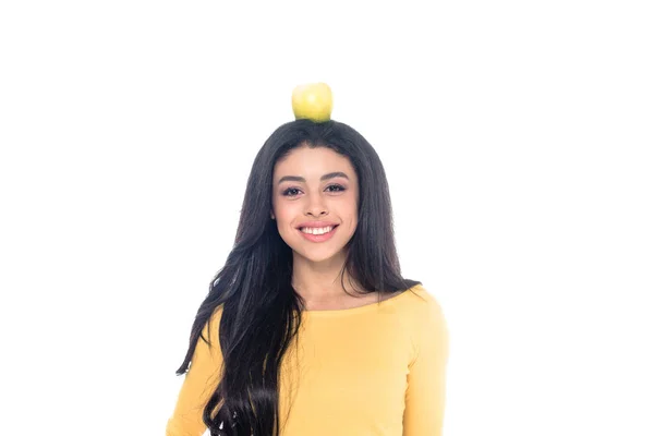 Beautiful happy young african american woman with apple on head smiling at camera isolated on white — Stock Photo