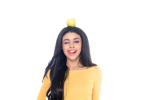 Feliz africana americana chica con manzana en la cabeza lamiendo labios aislado en blanco - foto de stock