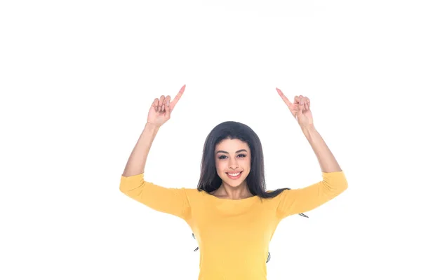 Feliz joven afroamericana mujer apuntando hacia arriba con los dedos y sonriendo a la cámara aislada en blanco - foto de stock