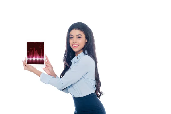 Hermosa chica afroamericana sosteniendo tableta digital con gráficos de negocios y sonriendo a la cámara aislada en blanco - foto de stock