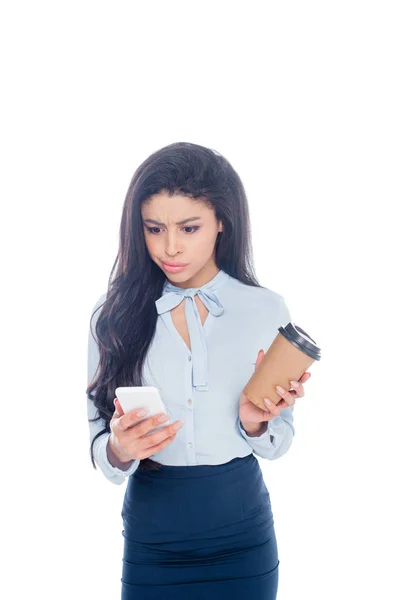 Joven mujer de negocios afroamericana sosteniendo café para ir y el uso de teléfono inteligente aislado en blanco - foto de stock