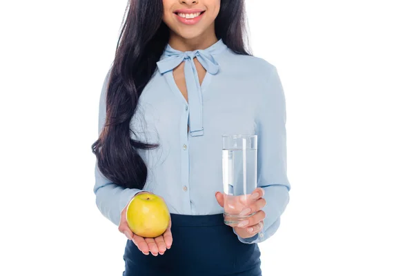 Abgeschnittene Aufnahme einer lächelnden Afroamerikanerin mit einem Glas Wasser und einem Apfel auf weißem Grund — Stockfoto