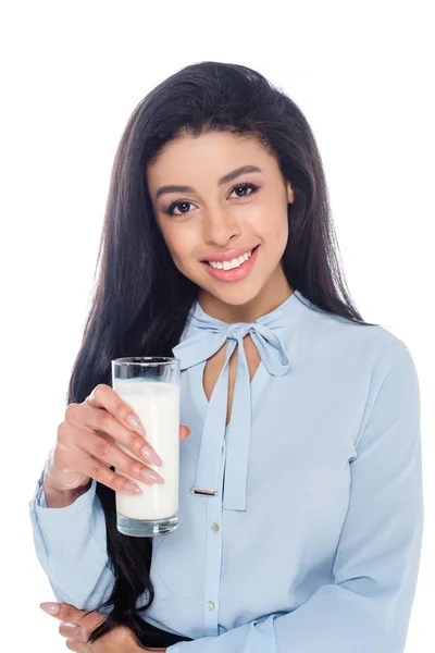 Hermosa chica afroamericana sosteniendo un vaso de leche y sonriendo a la cámara aislada en blanco - foto de stock