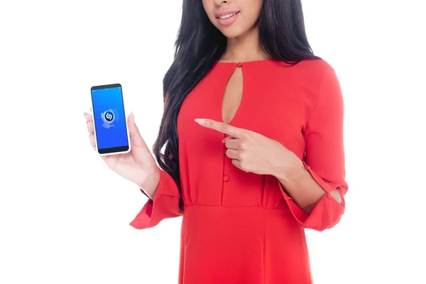 Vista parcial de la mujer en vestido rojo apuntando al teléfono inteligente con shazam aislado en blanco - foto de stock