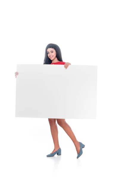 Smiling african american girl in red dress showing empty banner isolated on white — Stock Photo