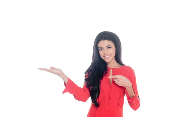 Feliz afroamericana joven en vestido rojo señalando con el dedo aislado en blanco - foto de stock