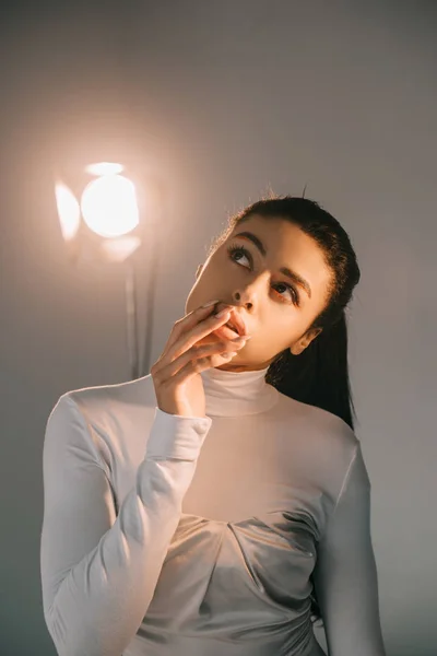 Menina americana africana bonita no pescoço de tartaruga branca posando em estúdio com holofotes — Fotografia de Stock