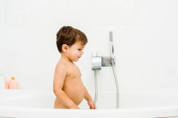 Маленький і милий хлопчик, що стоїть у білій ванній кімнаті — стокове фото