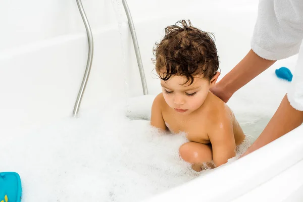 Mãos femininas lavar menino pequeno no banheiro branco — Fotografia de Stock
