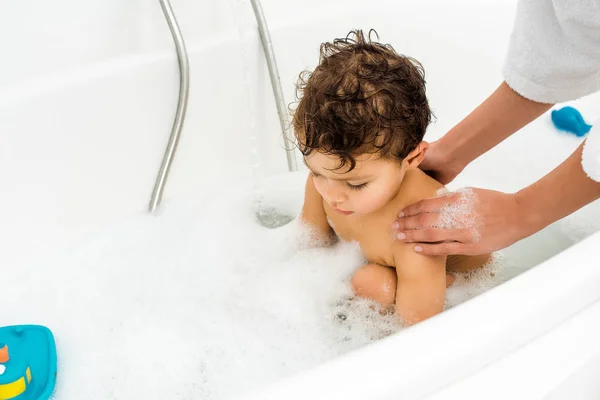 Female hands washing toddler boy in white bathroom — Stock Photo