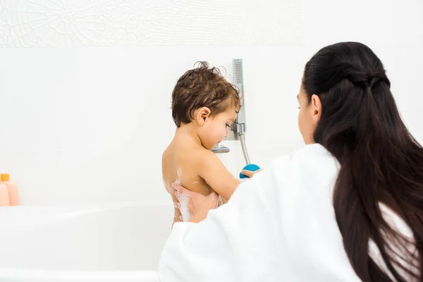 Mother with long hair washing son in white bathroom — Stock Photo