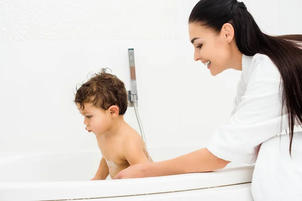 Mutter lächelt und schaut Sohn im Badezimmer an — Stockfoto