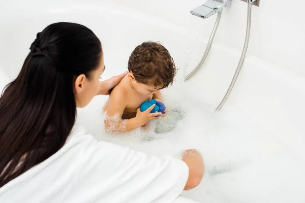 Жінка миє маленького хлопчика у ванній кімнаті з білого мармуру — стокове фото