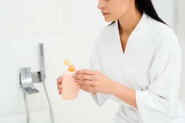 Woman holding bottle with lotion in white bathroom — Stock Photo
