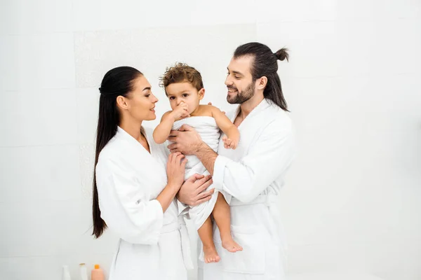 Mother and father looking at toddler son in white towel and smiling — Stock Photo