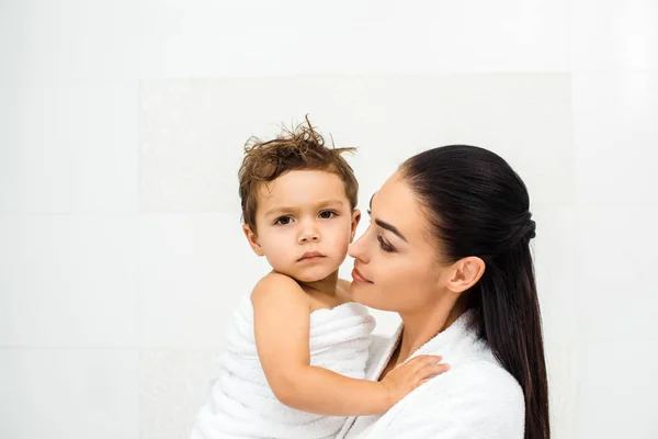 Nahaufnahme einer Mutter, die ihren kleinen Sohn im Handtuch auf weiß anschaut — Stockfoto