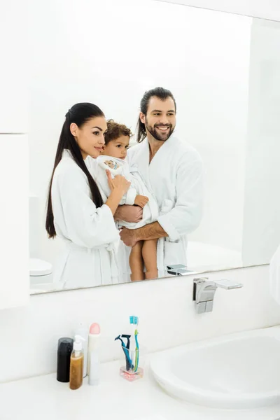 Famille regardant dans le miroir et souriant dans la salle de bain blanche — Photo de stock