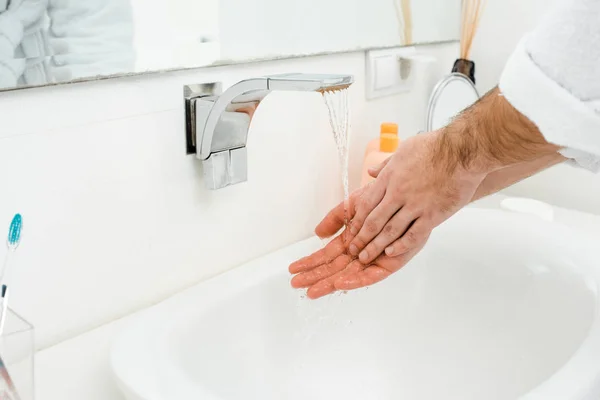 Manos masculinas bajo agua corriente en baño blanco - foto de stock