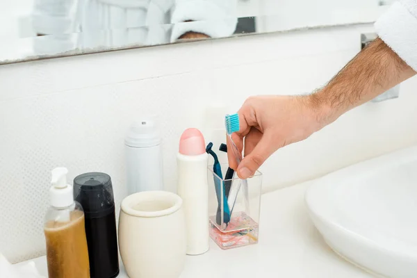 Close up male hand and different toiletries in bathroom — Stock Photo