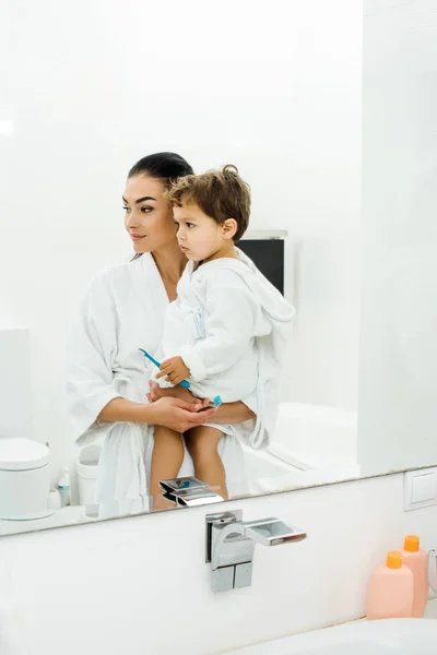 Mère et fils en peignoirs blancs se brossant les dents ensemble — Photo de stock