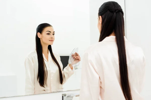 Beautiful woman with perfect skin looking in mirror at bathroom — Stock Photo