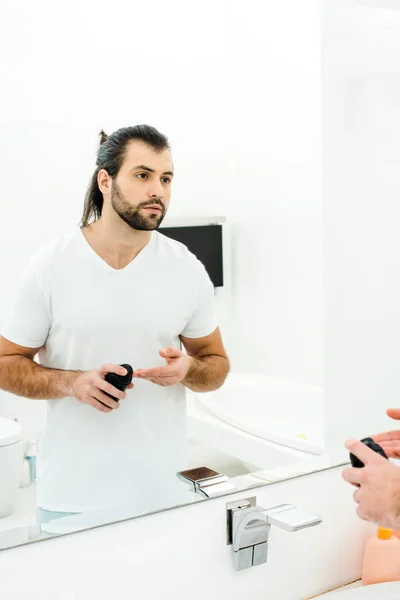 Homem bonito aplicando espuma de barbear nos dedos no banheiro — Fotografia de Stock