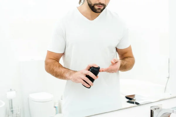 Hombre sosteniendo espuma de afeitar delante del espejo en el baño - foto de stock