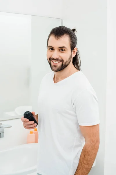 Homme tenant mousse à raser et souriant dans la salle de bain — Photo de stock