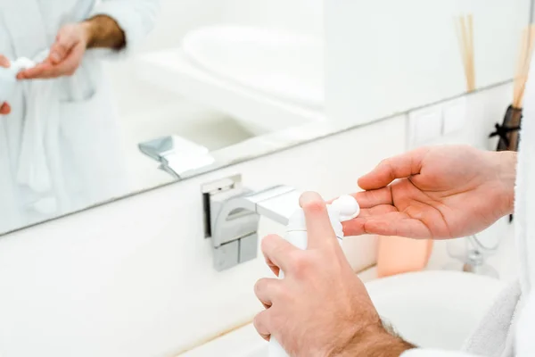 Mãos masculinas segurando espuma de barbear na frente do espelho no banheiro — Fotografia de Stock