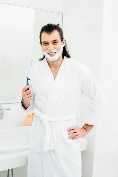 Bonito homem de barbear e sorrindo no banheiro — Fotografia de Stock