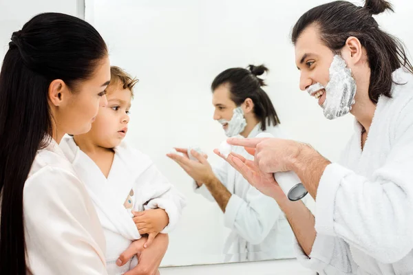 Красавчик, показывающий маленькому сыну пену для бритья. — стоковое фото